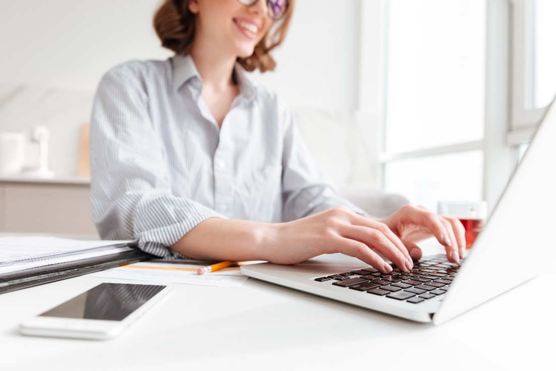 Young woman wearing a white blouse working on a laptop in a remote working hub