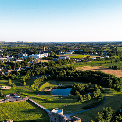 SIRO birds eye view of Roscommon Town on a sunny day, with Roscommon Castle in the foreground and town in the background.